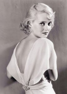 A very young Bette Davis in backless wrap gown with rosette at the waist.